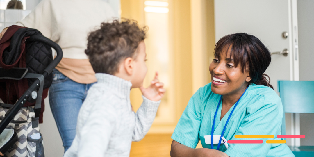 Healthcare worker kneeling to talk to a child in the waiting room.