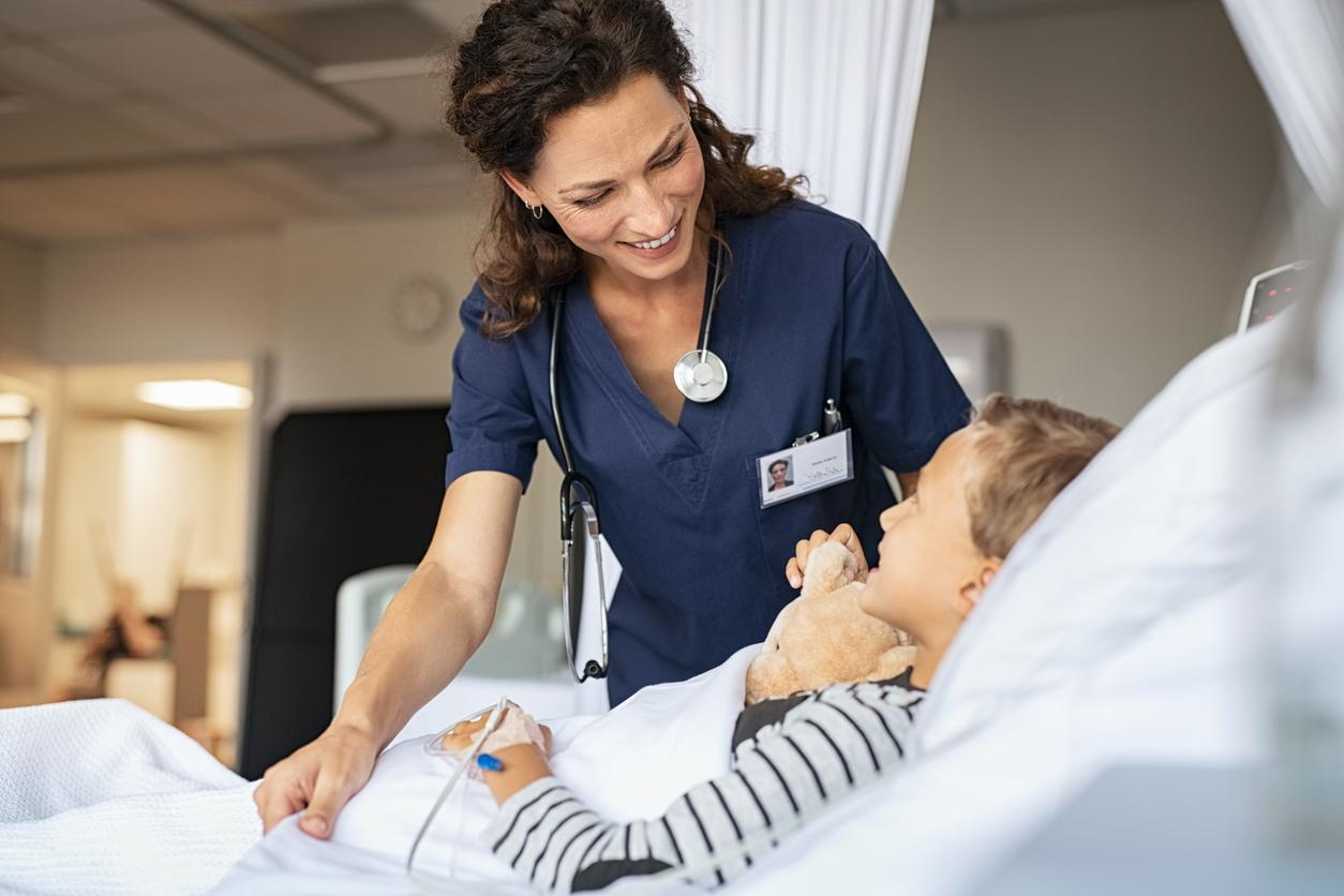 Nurse practitioner leaning over child patients bed