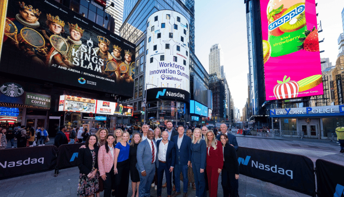 ShiftMed executives with health system partners posing in front of the illuminated NASDAQ sign during the 2025 Workforce Innovation Summit in New York City.