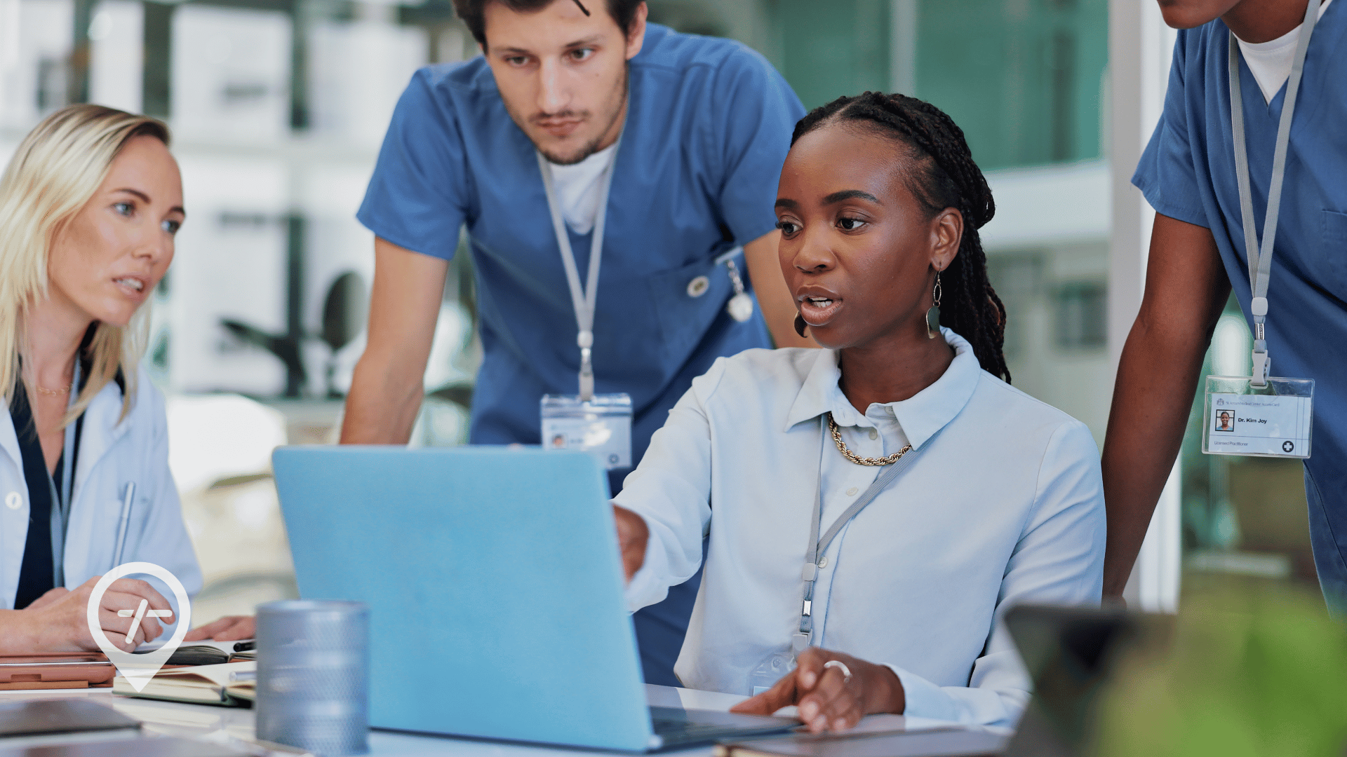 Doctors and nurses looking at a laptop within a hospital setting.