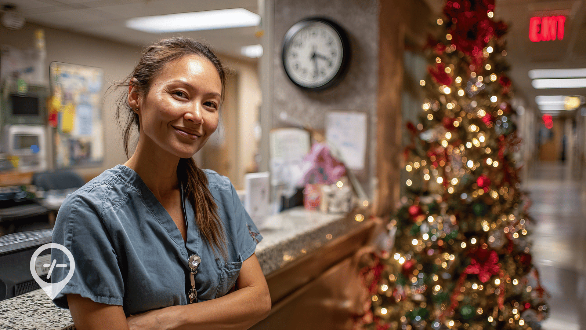 A nurse stands smiling near a nurses' station with a Christmas tree in the background to represent how to decline extra holiday nursing shifts without feeling the guilt.