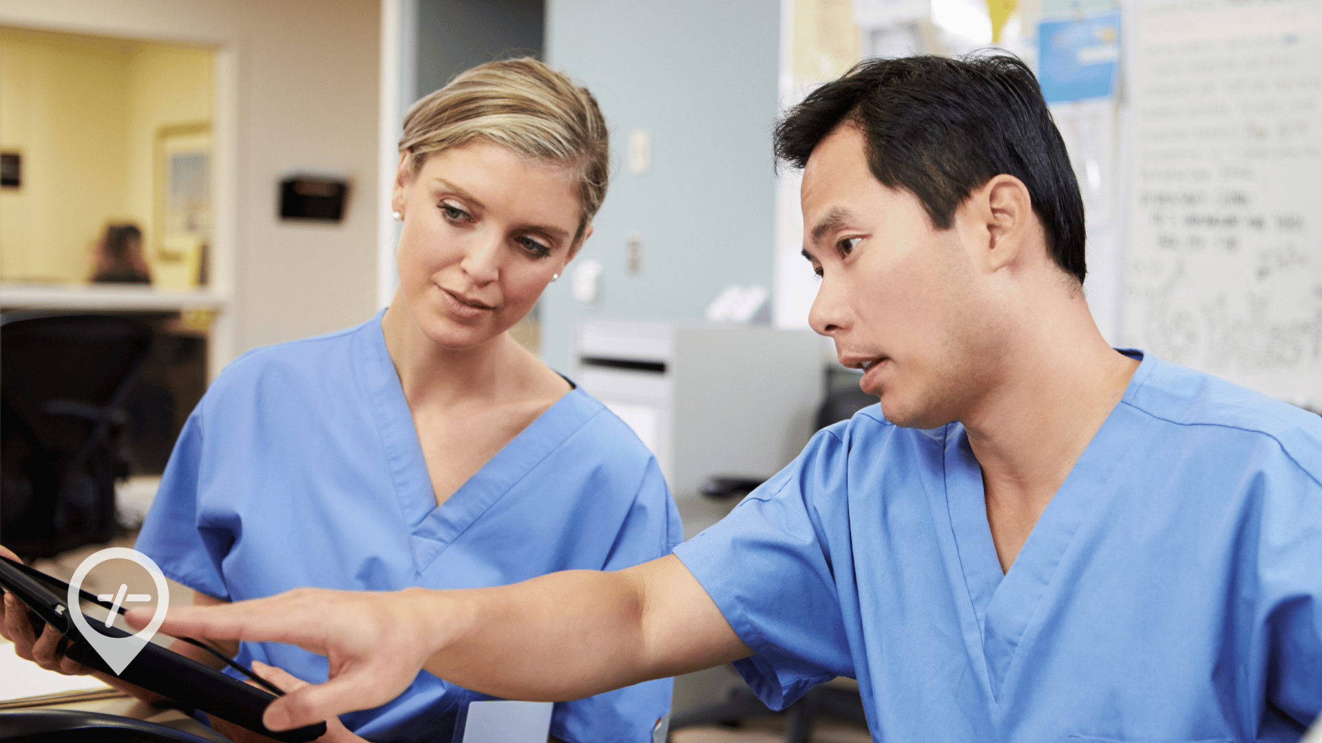 An image of a male nurse showing a female nurse how to access patient information on a mobile device.