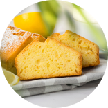 Sliced lemon cake on a plate, showcasing its moist texture and a fresh lemon.