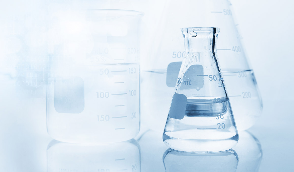 Laboratory glassware including beakers and a flask filled with clear liquid on a reflective surface.