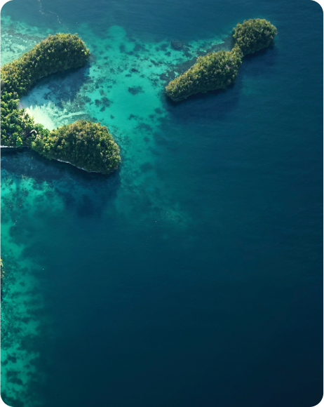 Aerial view of lush green islands surrounded by deep blue ocean waters, showcasing vibrant tropical nature and coastline.