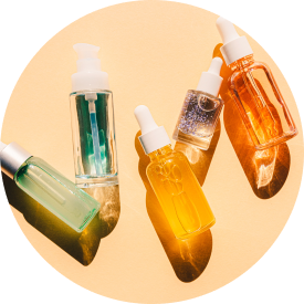  Assorted skincare oils in glass dropper bottles arranged on a circular surface, showcasing different colors and textures.