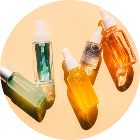  Assorted skincare oils in glass dropper bottles arranged on a circular surface, showcasing different colors and textures.