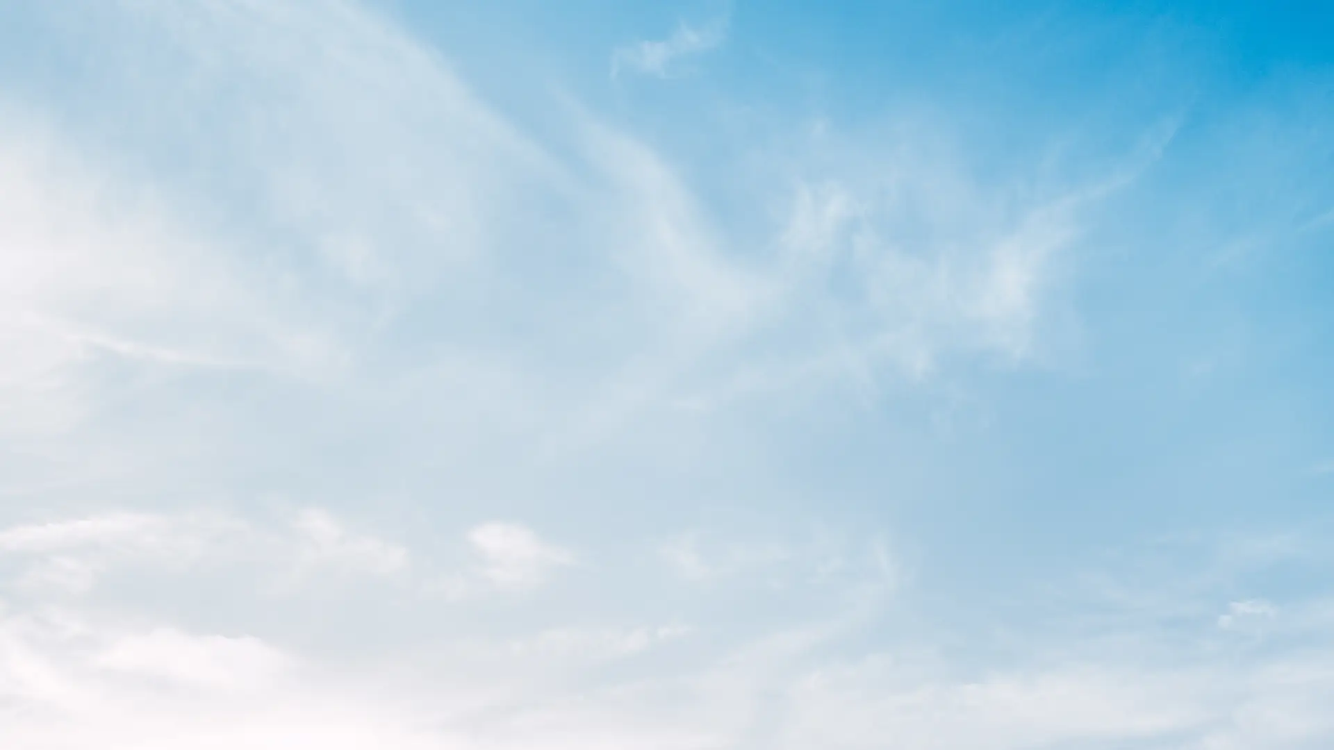  Clouds gracefully drift across a bright blue sky.