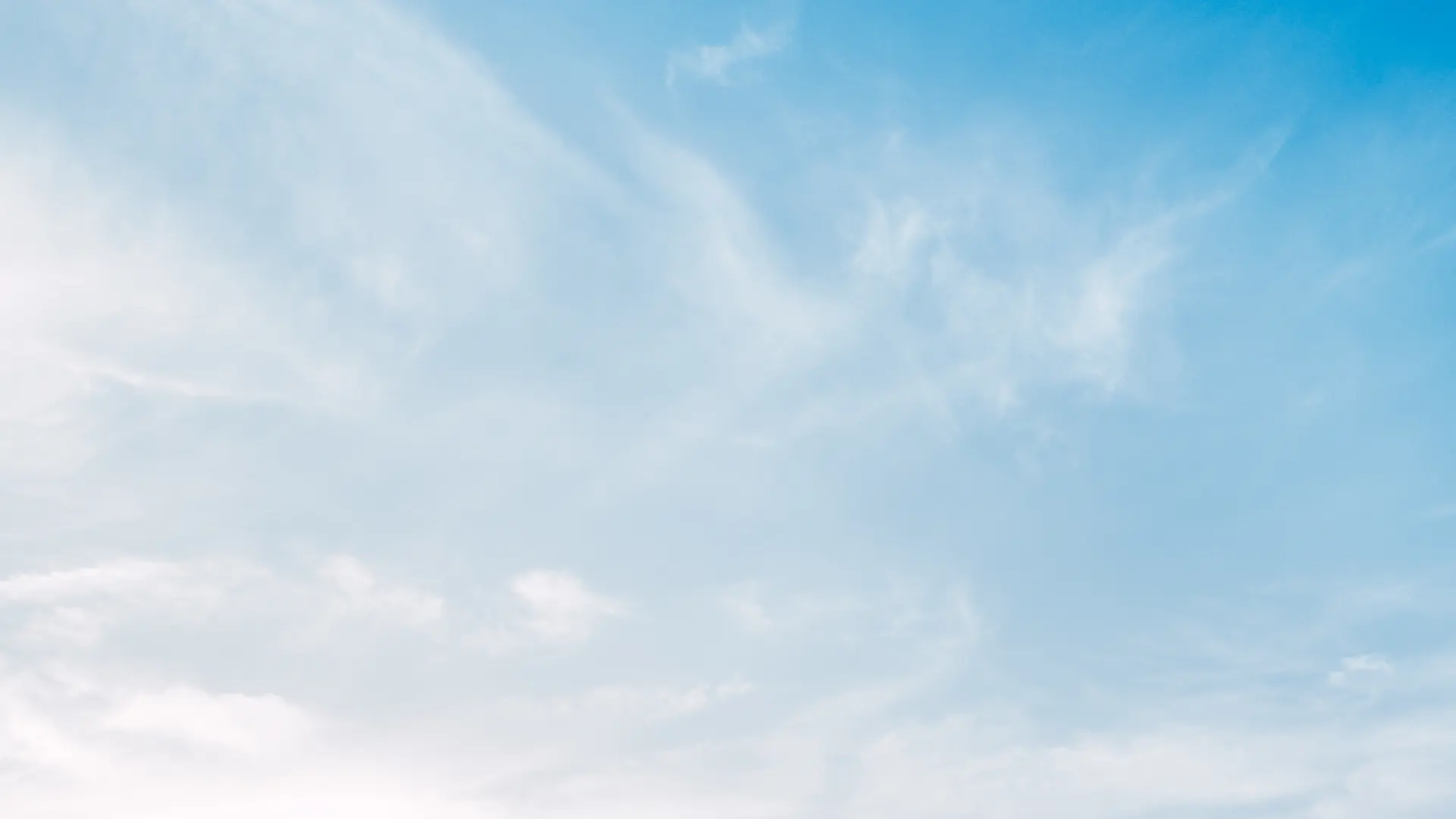  Clouds gracefully drift across a bright blue sky.