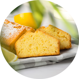  Sliced lemon cake on a plate, showcasing its moist texture and a fresh lemon.