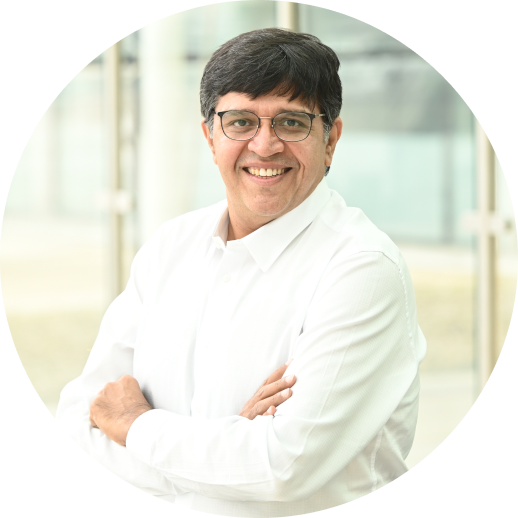 Smiling man wearing glasses and a white shirt, posing with arms crossed in front of a bright, modern background.
