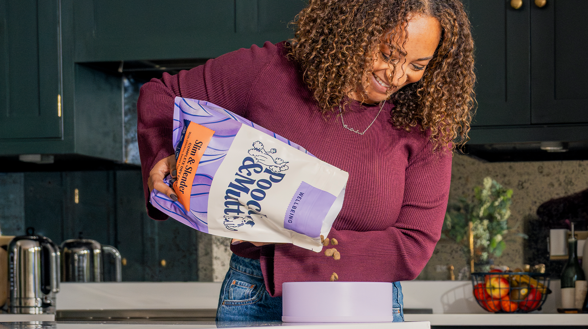 A dog owner pouring Pooch & Mutt's Slim & Slender Dry Food into a dog bowl.