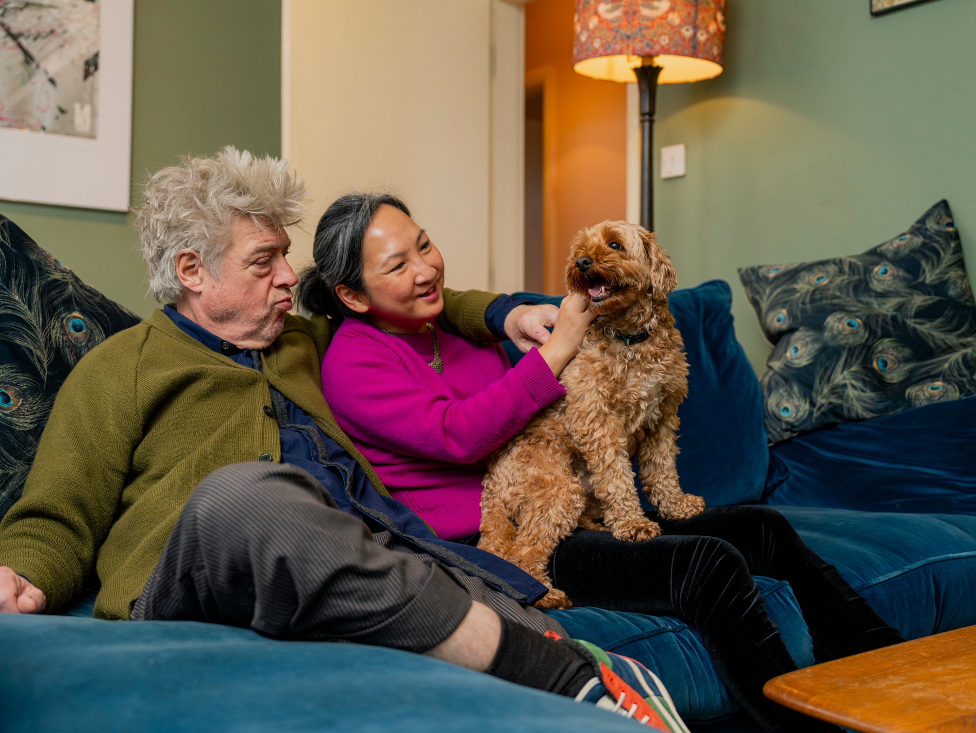 Couple sits on the sofa with a dog