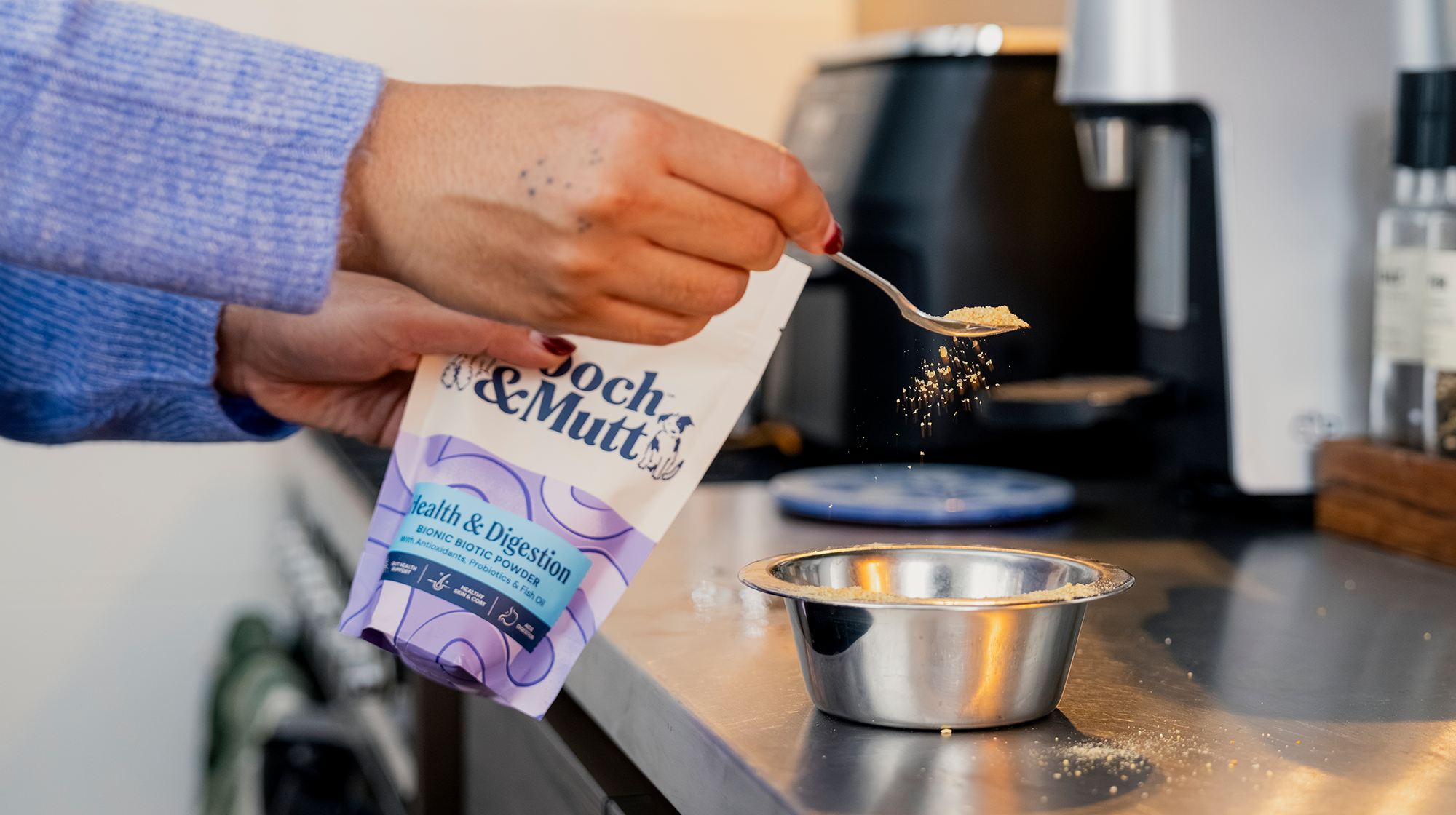 A dog owner sprinkles Pooch & Mutt's Health & Digestion Bionic Biotic Supplement powder on dog food.