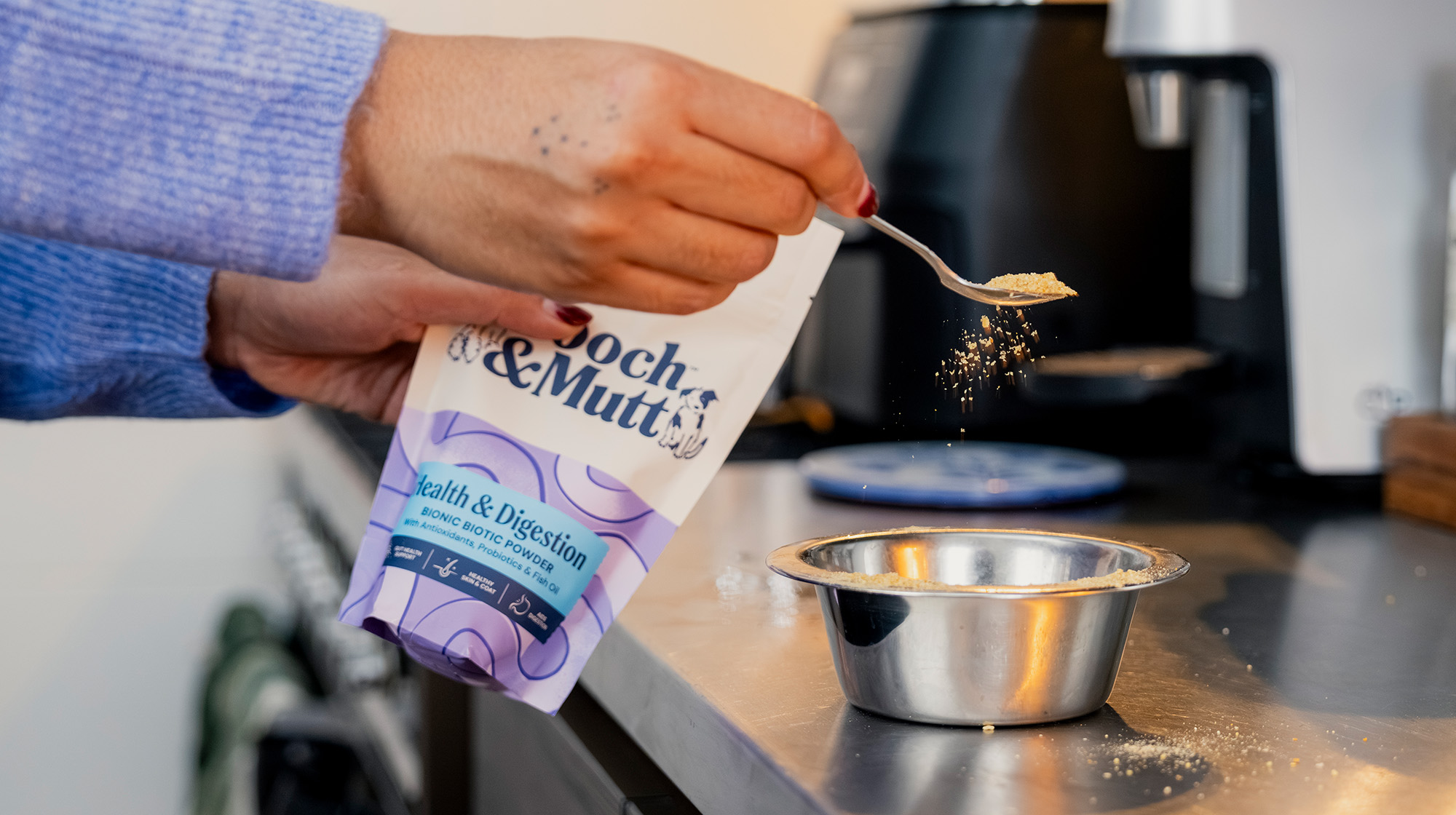 A dog owner sprinkles Pooch & Mutt Health & Digestion Bionic Biotic Supplement powder of a bowl of dog food.