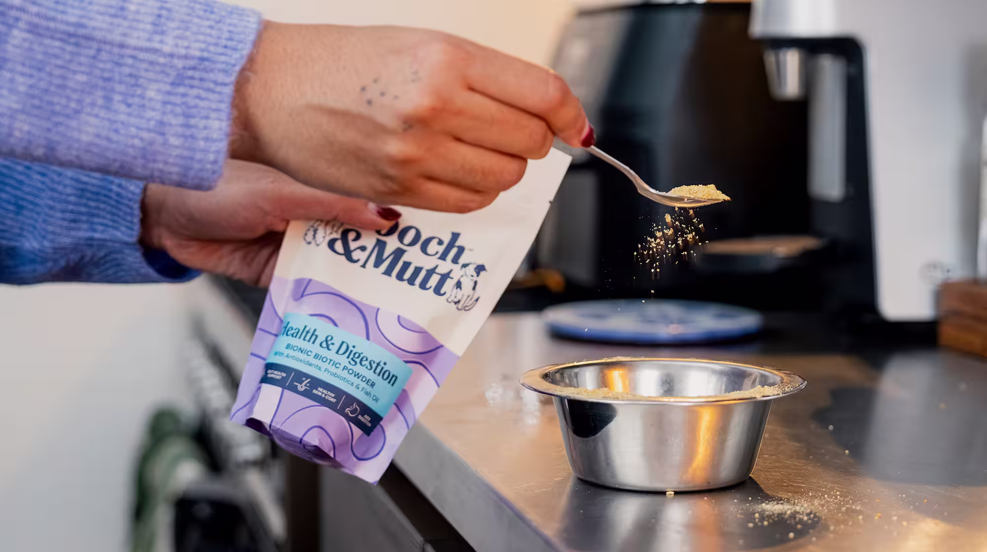 A dog owner sprinkles Pooch & Mutt Health & Digestion Bionic Biotic Supplement powder of a bowl of dog food.