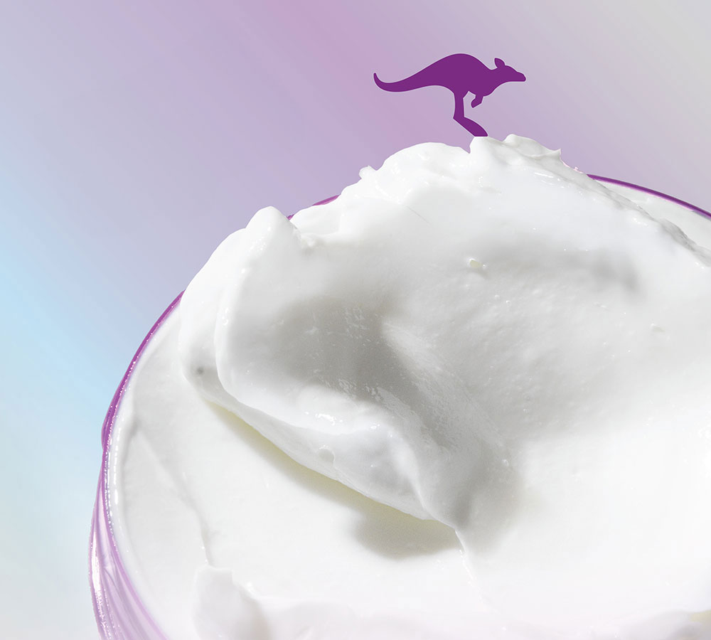 Primer plano de Aussie Supercharged Repair Mascarilla crema blanca con canguro morado, sobre fondo degradado morado y azul.