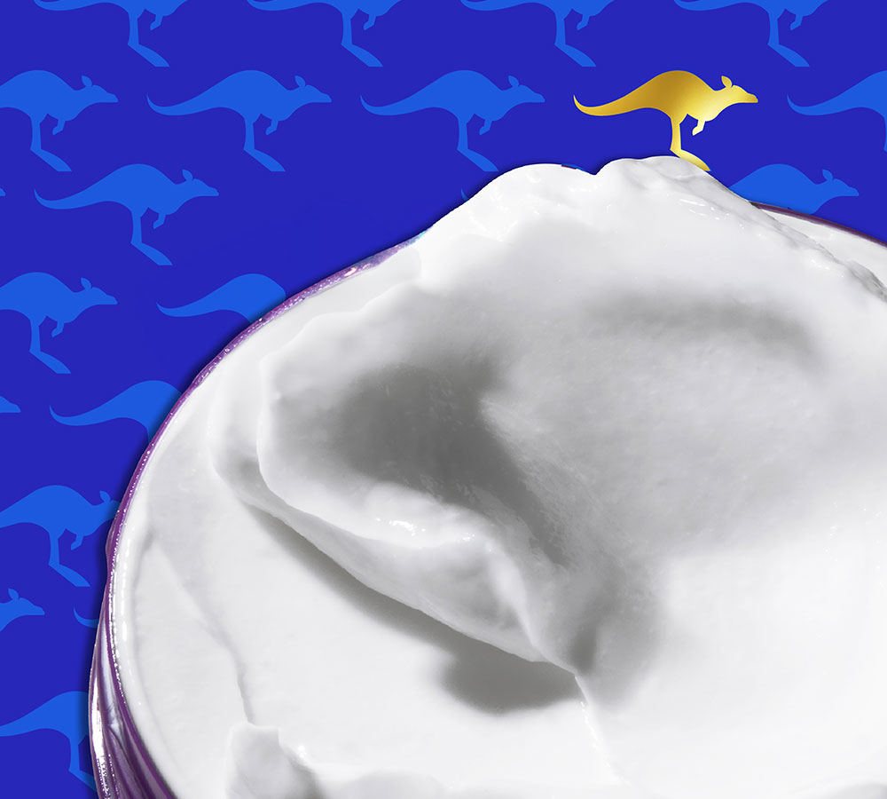 Primer plano de una Aussie Hidratación Profunda Mascarilla con un canguro dorado encima, sobre un fondo azul.