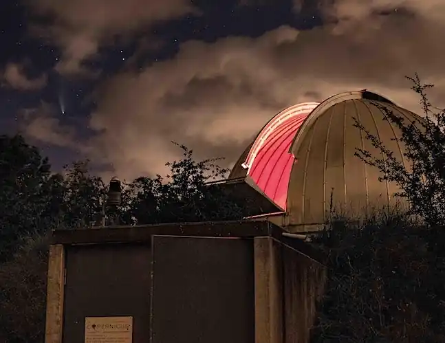 Komeet NEOWISE over de sterrenwacht op een half bewolkte avond