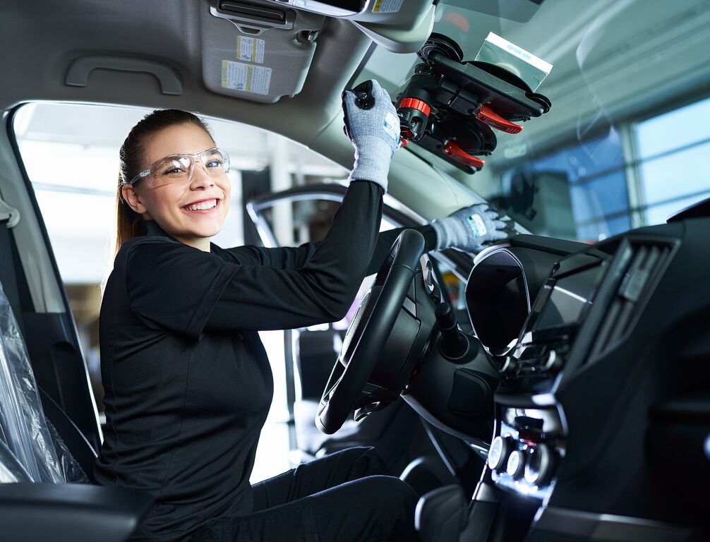 Technicienne souriante dans une voiture remplacant un parebrise