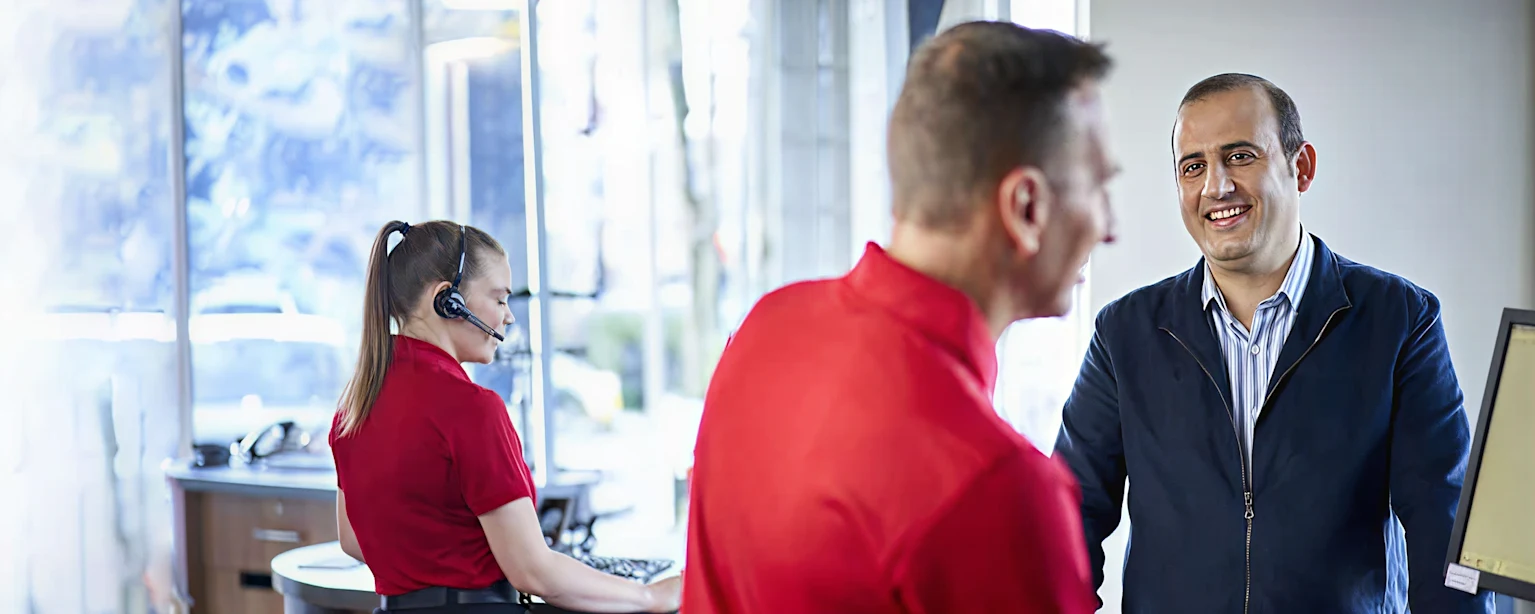 Reception area of a center with a receptionist on the phone and a man receiving a customer