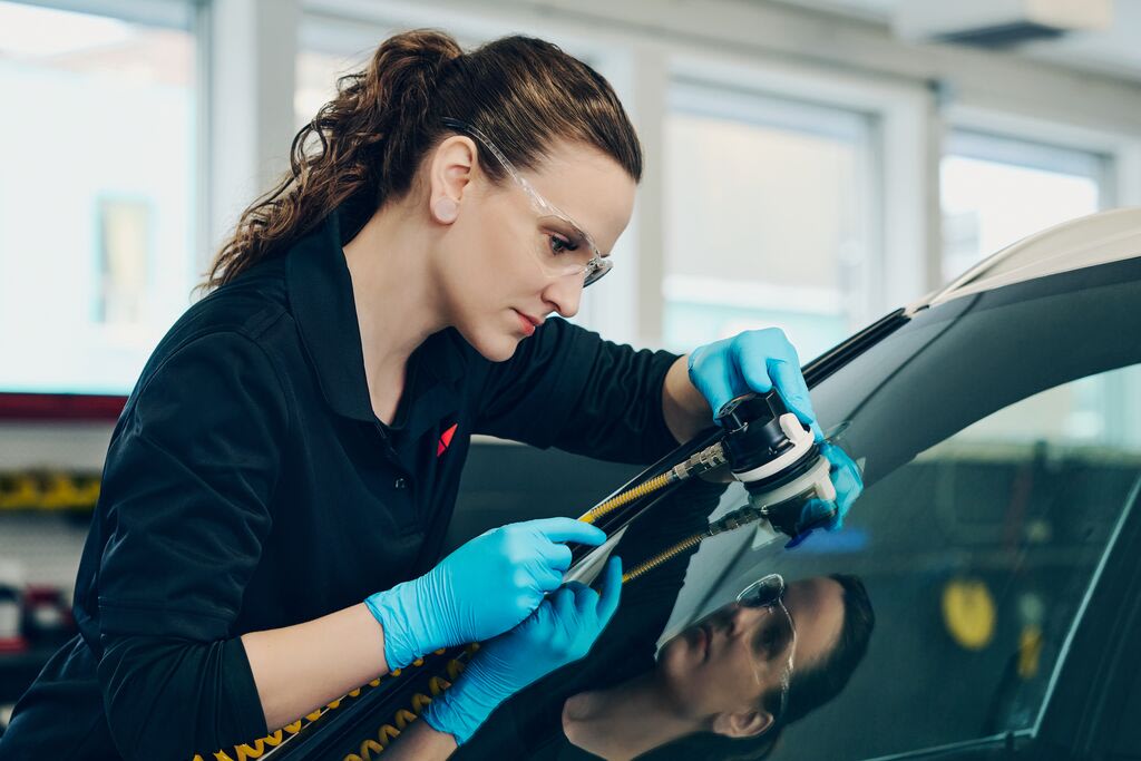 Side view of a woman applying a tool to a broken window