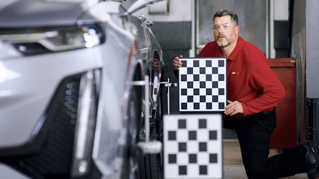 Technician calibrating cameras on the side of a car
