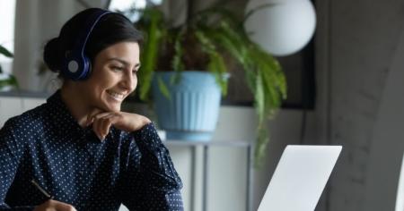 Woman sitting at a desk, smiling while looking at her computer screen powered by Splashtop remotely