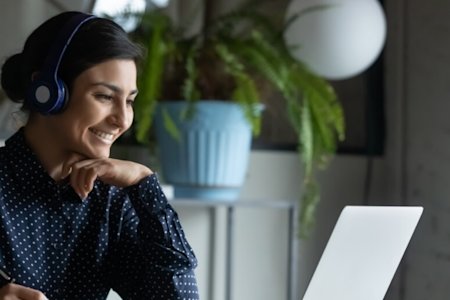 Woman sitting at a desk, smiling while looking at her computer screen powered by Splashtop remotely
