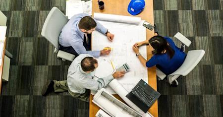 Project managers looking over plans on a desk.