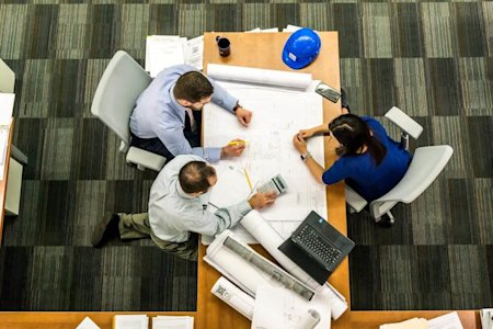 Project managers looking over plans on a desk.