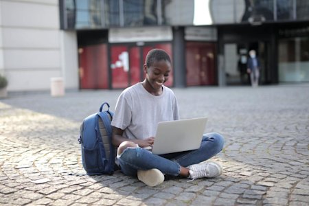 A student studying in a courtyard on a laptop using remote access software.