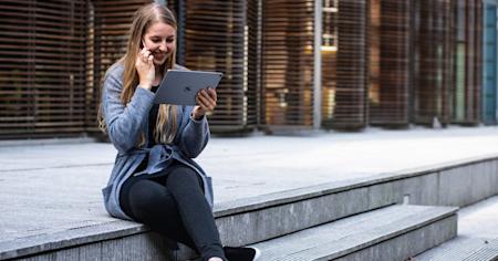 A woman sitting on steps outside using an iPad.