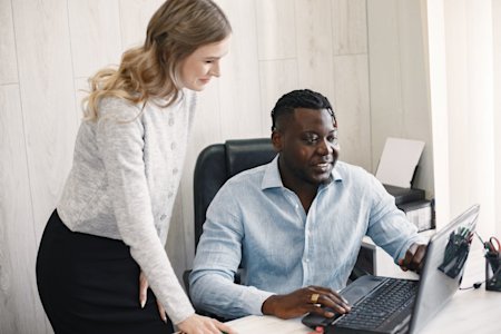 Two coworkers viewing a laptop screen and smiling.