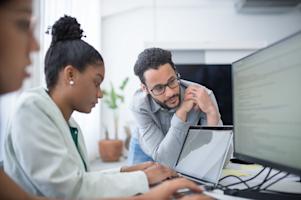 An IT worker supporting a user at their workstation.