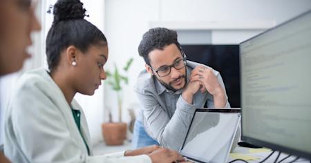 An IT worker supporting a user at their workstation.