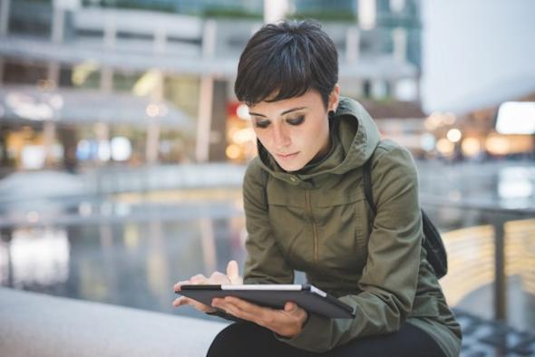 IT woman sitting on a ledge using Splashtop to remotely access computer with tablet