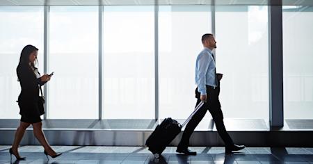Business professionals walking through an airport terminal, illustrating the impact of rising business travel costs.