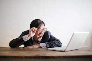 A person with a shocked, angry reaction while looking at their computer.