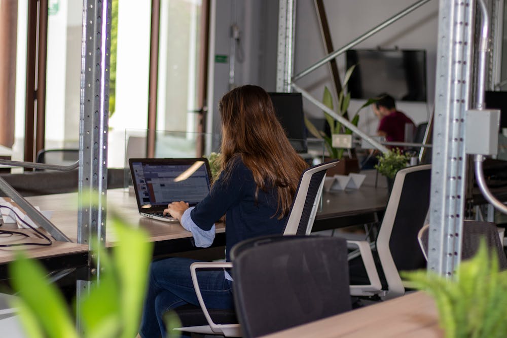 A woman sitting in an office working on a laptop.