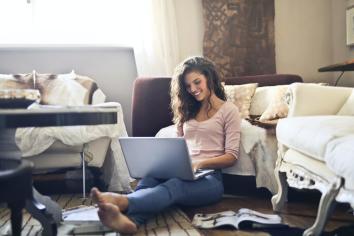 A young woman working from home in her living room using Splashtop on her laptop