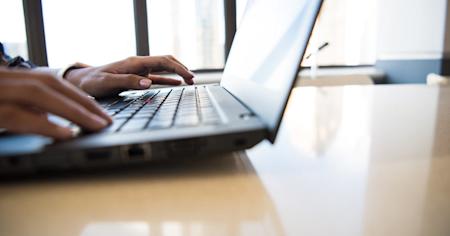 A person typing on a Windows PC laptop.