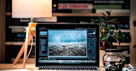 A Mac laptop displaying a photo editing software on a desktop in a library.