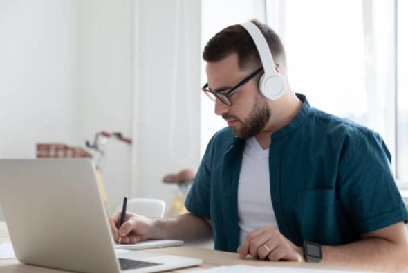 A man wearing headphones working on a Macbook to use Splashtop remote desktop software.