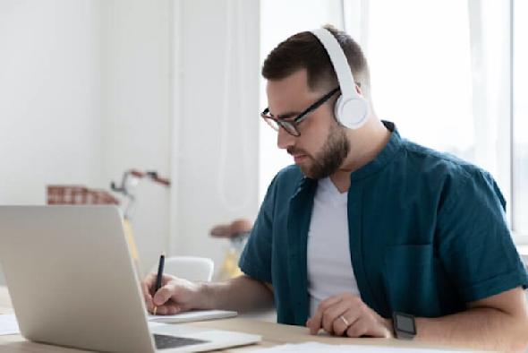 A man wearing headphones working on a Macbook to use Splashtop remote desktop software.