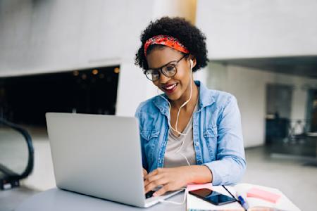 Focused woman in IT at desk with earbuds on, diligently working remotely with Splashtop