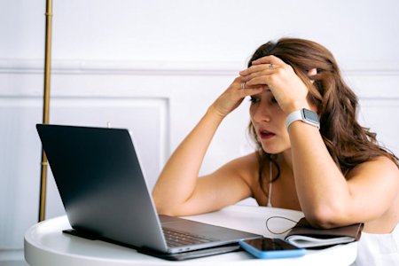 A person looking stressed at their work computer.