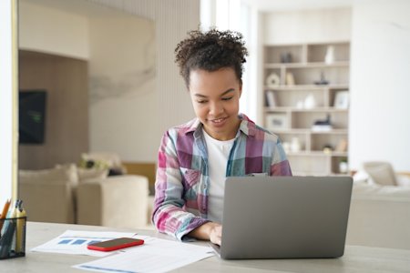 A young woman working on a laptop during a remote session at a desk.