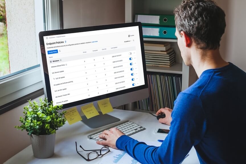 A person is using a desktop computer displaying the Splashtop management dashboard, specifically the Endpoint Policies section with various policy settings and options visible on the screen.