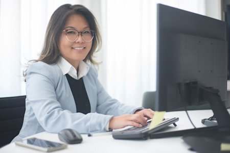A woman smiling while working on her computer in an office.